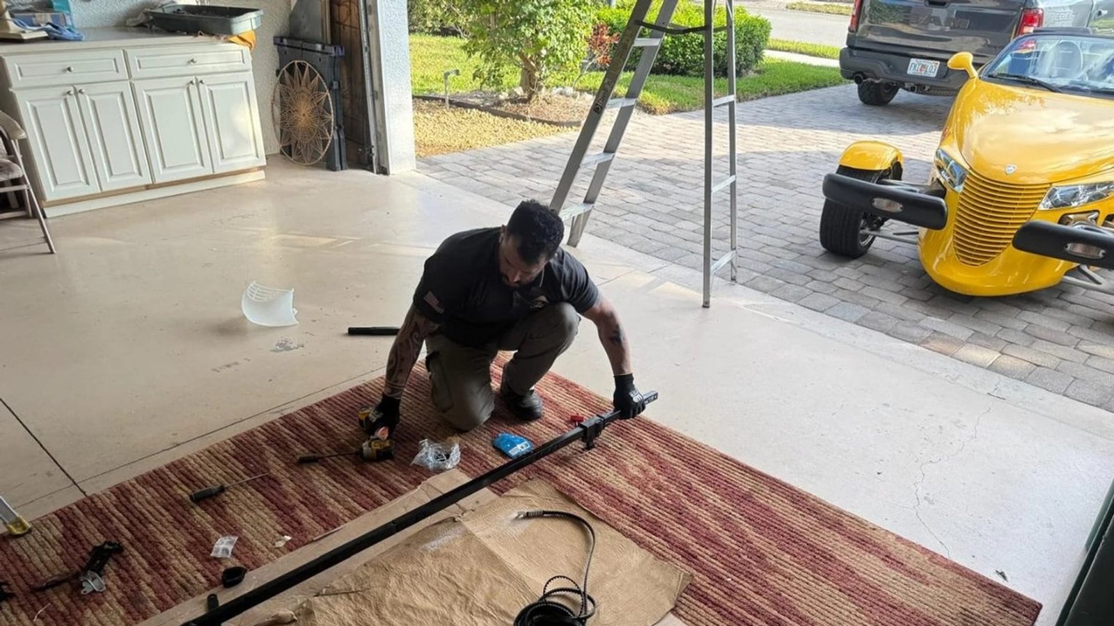 Technician kneeling on a garage floor to assemble door hardware