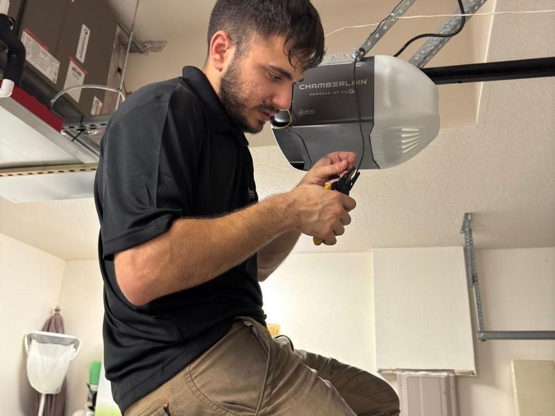 Technician adjusting the motor unit of a ceiling-mounted garage door opener