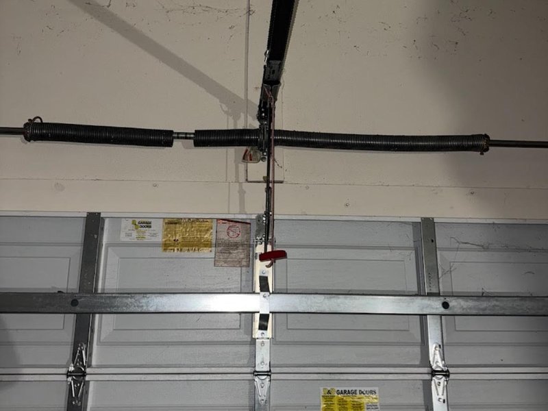 Torsion spring and cable fittings above a closed garage door