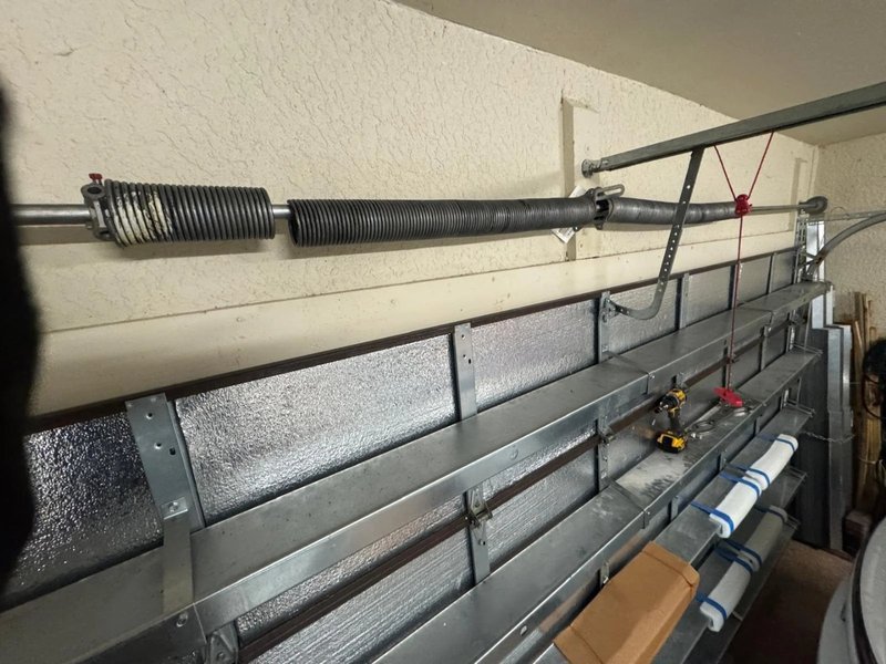 Torsion spring on a steel shaft above an insulated garage door section